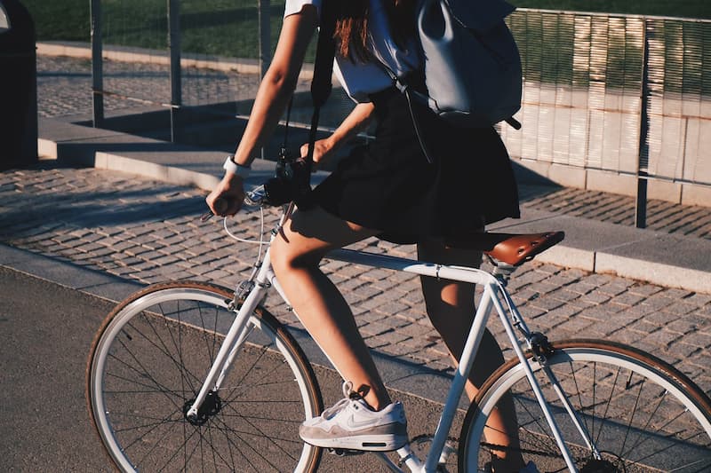 Une cycliste sur son vélo avec un accessoire indispensable: la sacoche de coursier.