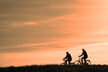 deux cyclistes à vélo au coucher de soleil avec leurs accessoires